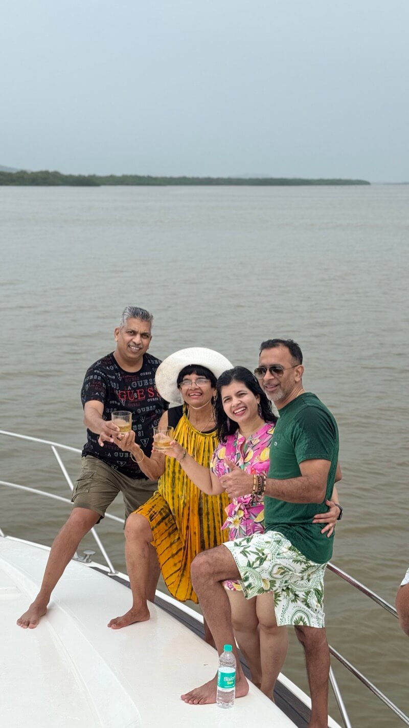 Four family members raising a toast together on the bow of the Ambassador yacht, Mandovi River, Goa