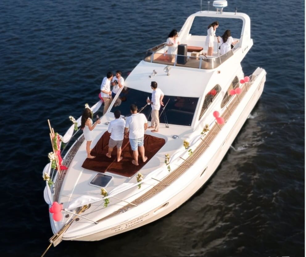 Guests in white gathered on the decks of the Ambassador yacht at golden hour on the Mandovi River, Goa