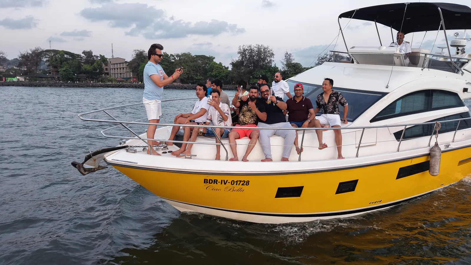 Guests aboard the Ciao Bella yellow yacht at golden hour, Goa