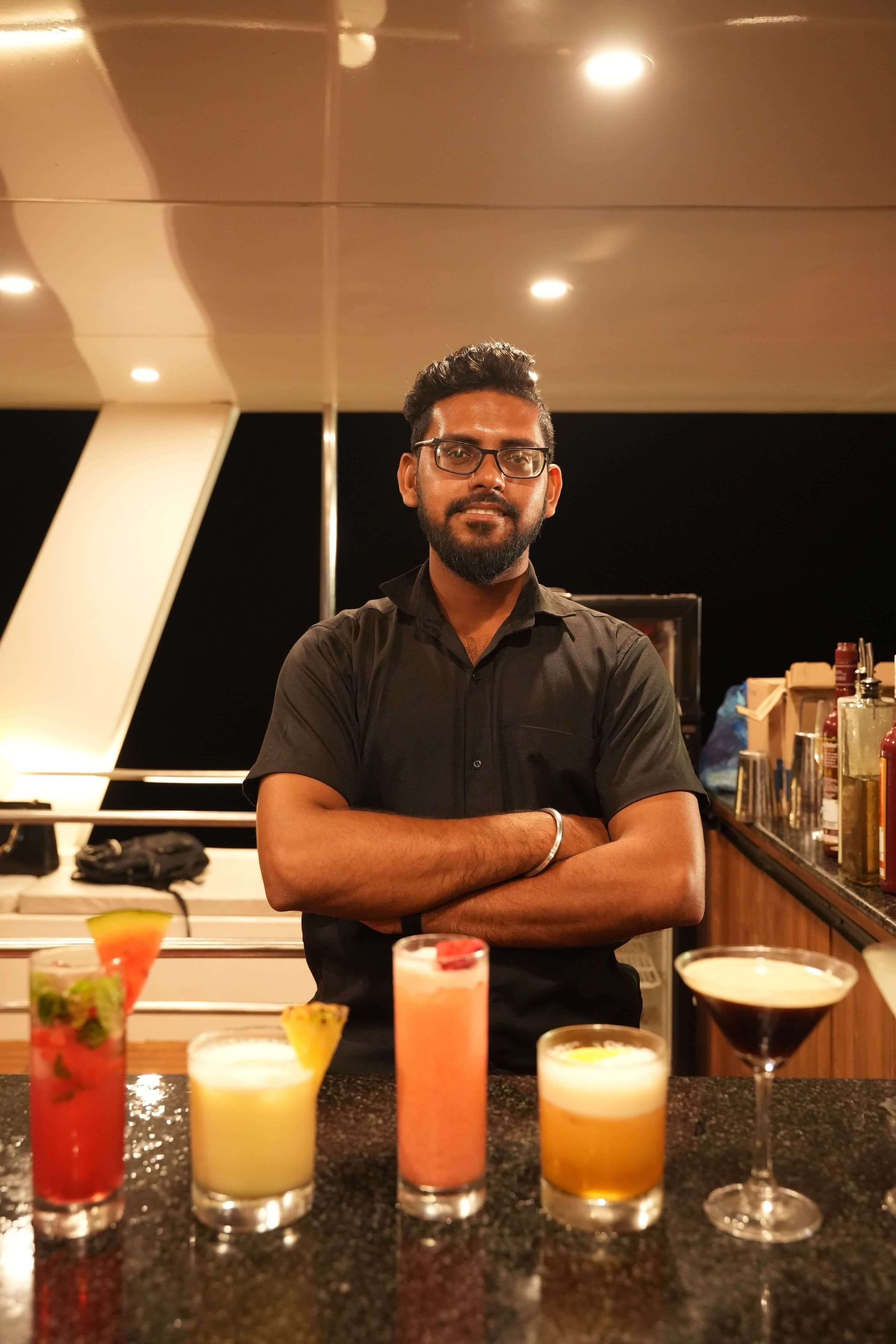 Leo Mar's bartender behind a lineup of fresh cocktails at the top-deck bar